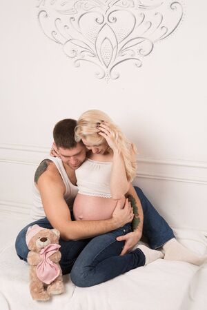 Beautiful pregnant couple in love on the background. Hands of husband on the tummy of his pregnant wife. Young man tenderly stroked pregnant belly of his wife. Husband kissing pregnant belly.の写真素材