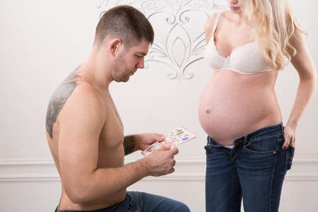 Beautiful pregnant couple in love on the background. Hands of husband on the tummy of his pregnant wife. Young man tenderly stroked pregnant belly of his wife. Husband kissing pregnant belly.の写真素材