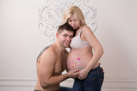 Beautiful pregnant couple in love on the background. Hands of husband on the tummy of his pregnant wife. Young man tenderly stroked pregnant belly of his wife. Husband kissing pregnant belly.の写真素材