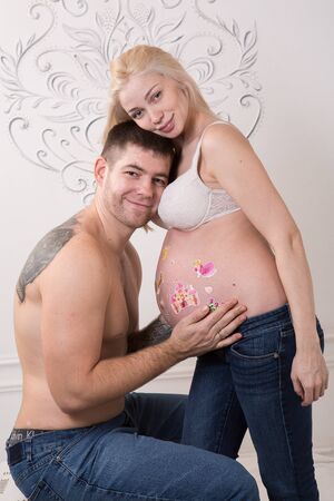 Beautiful pregnant couple in love on the background. Hands of husband on the tummy of his pregnant wife. Young man tenderly stroked pregnant belly of his wife. Husband kissing pregnant belly.の写真素材