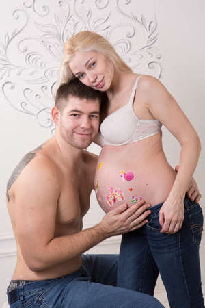 Beautiful pregnant couple in love on the background. Hands of husband on the tummy of his pregnant wife. Young man tenderly stroked pregnant belly of his wife. Husband kissing pregnant belly.の写真素材