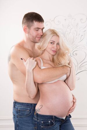 Beautiful pregnant couple in love on the background. Hands of husband on the tummy of his pregnant wife. Young man tenderly stroked pregnant belly of his wife. Husband kissing pregnant belly.の写真素材