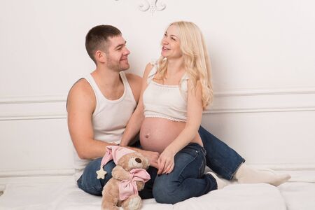 Beautiful pregnant couple in love on the background. Hands of husband on the tummy of his pregnant wife. Young man tenderly stroked pregnant belly of his wife. Husband kissing pregnant belly.の写真素材