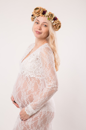 Happy pregnant young woman in love on the background. Hands on the tummy. Young mom tenderly stroked pregnant belly with unborn baby.の写真素材