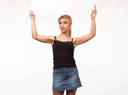 Young surprised woman portrait of a confident businesswoman showing presentation, pointing placard gray background. Ideal for banners, registration forms, presentation, landings, presenting concept.の写真素材