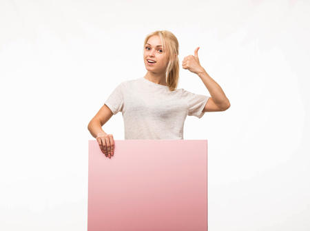Young confident woman portrait of a confident businesswoman showing presentation, pointing placard gray background. Ideal for banners, registration forms, presentation, landings, presenting concept.の写真素材