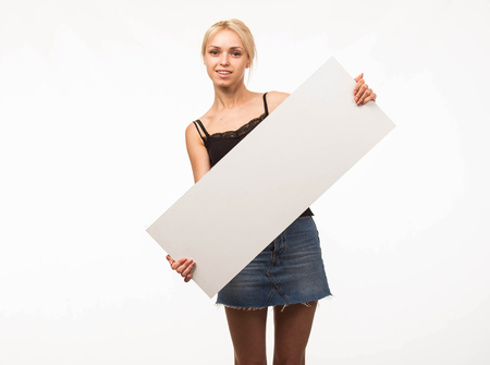 Young happy woman portrait of a confident businesswoman showing presentation, pointing placard gray background. Ideal for banners, registration forms, presentation, landings, presenting concept.の写真素材