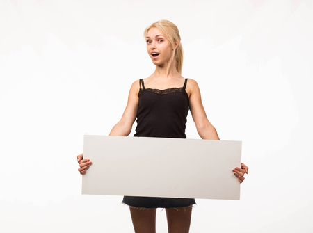 Young surprised woman portrait of a confident businesswoman showing presentation, pointing placard gray background. Ideal for banners, registration forms, presentation, landings, presenting concept.の写真素材