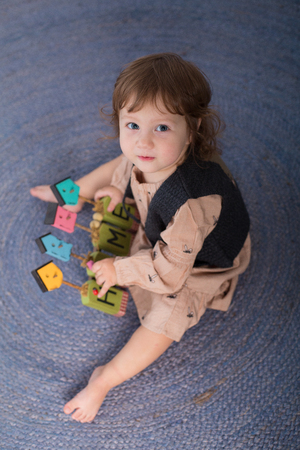 Little happy girl playing with toy on floor. Kindergarten.の写真素材