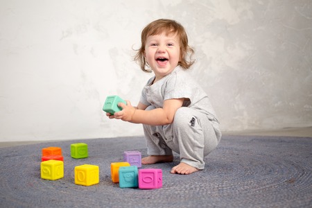 Little happy girl playing with toy on floor. Kindergarten.の写真素材