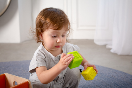 Little happy girl playing with toy on floor. Kindergarten.の写真素材