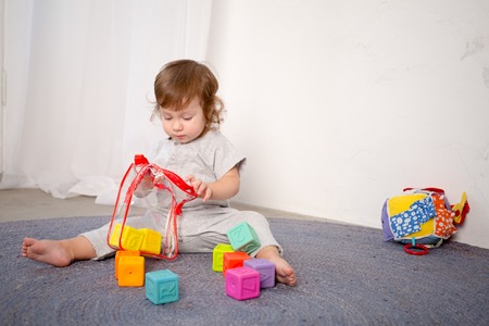 Little happy girl playing with toy on floor. Kindergarten.の写真素材