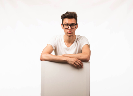 Young confident man portrait of a businessman showing presentation, pointing paper placard gray background. Ideal for banners, registration forms, presentation, landings, presenting concept.の写真素材