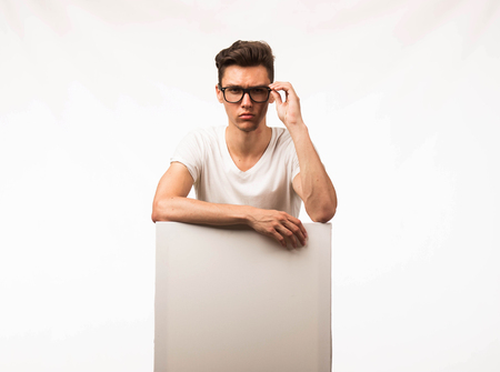 Young confident man portrait of a businessman showing presentation, pointing paper placard gray background. Ideal for banners, registration forms, presentation, landings, presenting concept.の写真素材