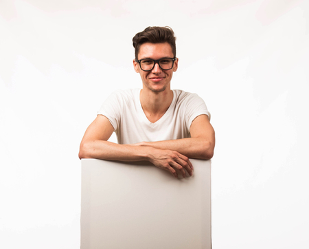 Young happy man portrait of a confident businessman showing presentation, pointing paper placard gray background. Ideal for banners, registration forms, presentation, landings, presenting concept.の写真素材