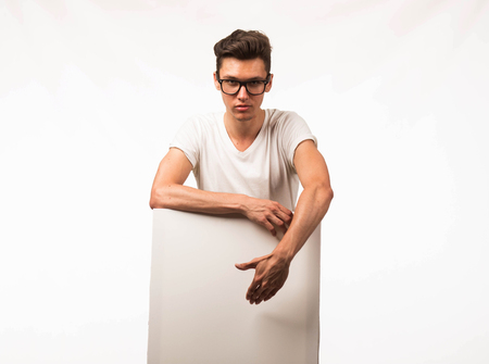 Young confident man portrait of a businessman showing presentation, pointing paper placard gray background. Ideal for banners, registration forms, presentation, landings, presenting concept.の写真素材