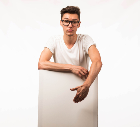 Young surprised man portrait of a confident businessman showing presentation, pointing paper placard gray background. Ideal for banners, registration forms, presentation, landings, presenting concept.の写真素材
