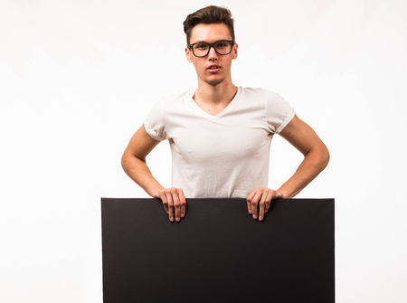 Young curious man portrait of a confident businessman showing presentation, pointing paper placard gray background. Ideal for banners, registration forms, presentation, landings, presenting concept.の写真素材