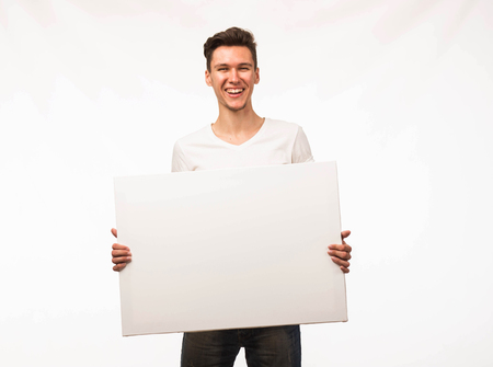 Young cheerful man portrait of a confident businessman showing presentation, pointing paper placard gray background. Ideal for banners, registration forms, presentation, landings, presenting concept.の写真素材
