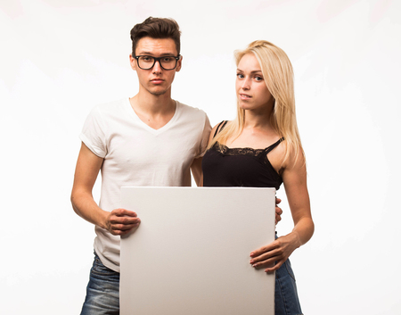 Young confident couple portrait of a businessman showing presentation, pointing paper placard gray background. Ideal for banners, registration forms, presentation, landings, presenting concept.の写真素材