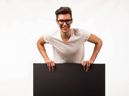 Young cheerful man portrait of a confident businessman showing presentation, pointing paper placard gray background. Ideal for banners, registration forms, presentation, landings, presenting concept.の写真素材