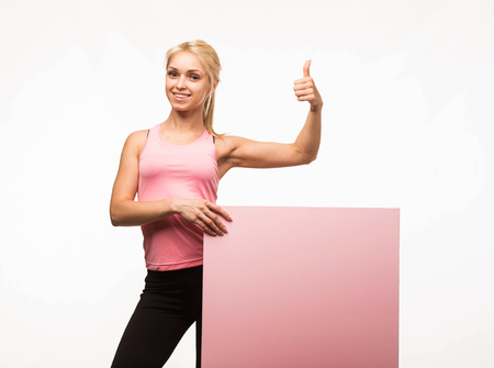 Young confident woman portrait of a businesswoman showing presentation, pointing placard gray background. Ideal for banners, registration forms, presentation, landings, presenting concept.の写真素材