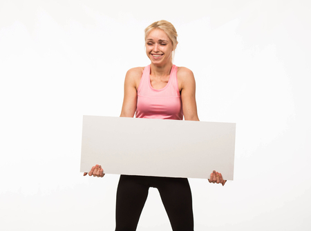 Young playful woman portrait of a confident businesswoman showing presentation, pointing placard gray background. Ideal for banners, registration forms, presentation, landings, presenting concept.の写真素材