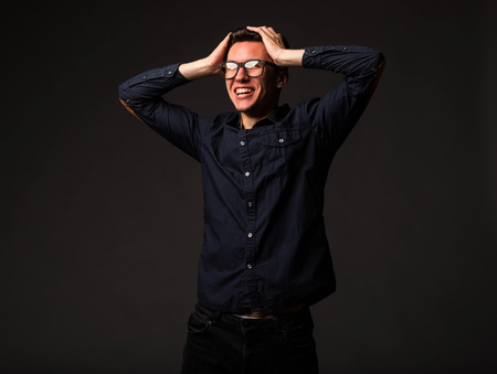 Young pensive man portrait of a confident businessman showing by hands on a black background. Ideal for banners, registration forms, presentation, landings, presenting concept.の写真素材