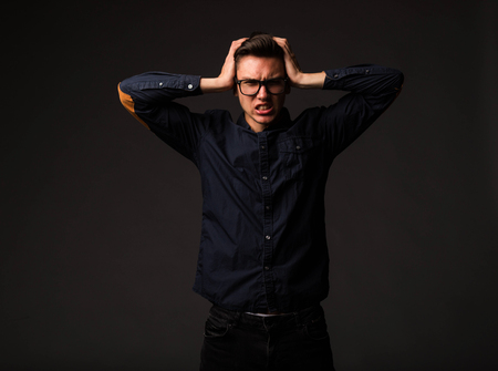Young angry man portrait of a confident businessman showing by hands on a black background.の写真素材