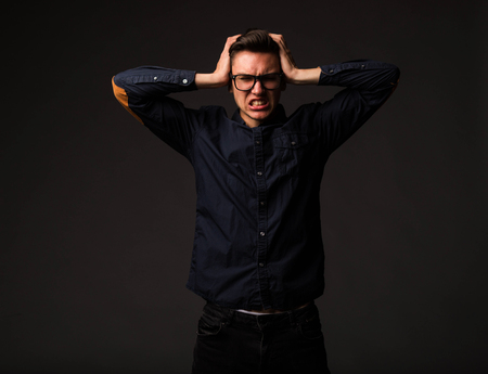 Young angry man portrait of a confident businessman showing by hands on a black background. Ideal for banners, registration forms, presentation, landings, presenting concept.の写真素材