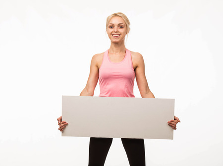 Young glad woman portrait of a confident businesswoman showing presentation, pointing placard gray background. Ideal for banners, registration forms, presentation, landings, presenting concept.の写真素材
