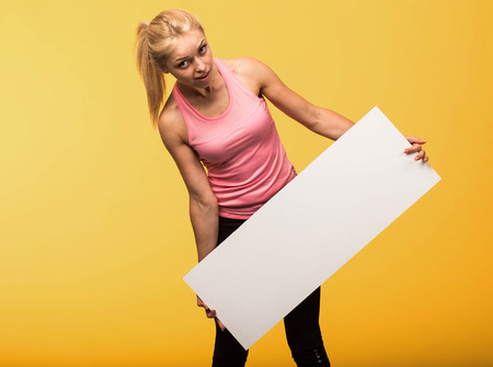 Young surprised woman portrait of a confident businesswoman showing presentation, pointing placard yellow background. Ideal for banners, registration forms, presentation, landings, presenting concept.の写真素材