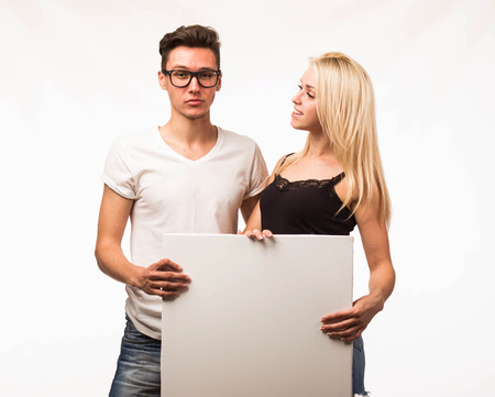 Young happy couple portrait of a confident businessman showing presentation, pointing paper placard gray background. Ideal for banners, registration forms, presentation, landings, presenting concept.の写真素材