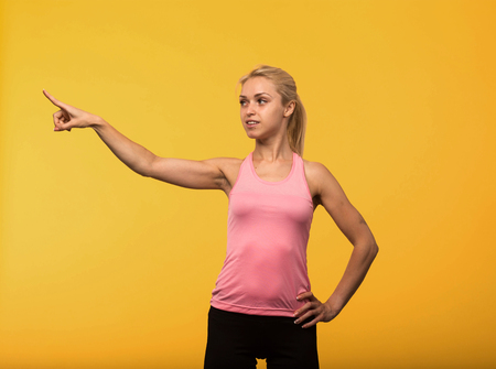 Young glad woman portrait of a confident businesswoman showing by hands on a yellow background. Ideal for banners, registration forms, presentation, landings, presenting conceptの写真素材