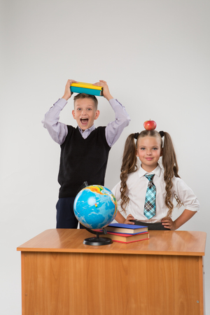 Happy boy and girl standing at a school desk, isolated on white background. Ideal for banners, registration forms, presentation, landings, presenting concept.の写真素材
