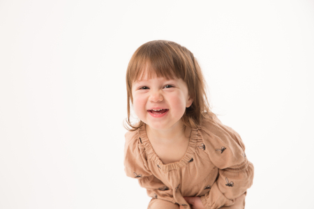 Cute little girl in beige dress isolated on white background. Portrait of happy little girl on white background. Sweet girl with curly hair.の写真素材