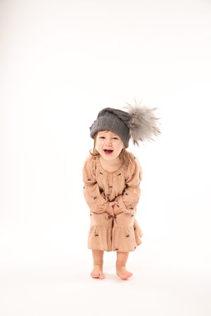 Portrait of happy little girl. Cute little girl in beige dress in a gray hat isolated on white background.の写真素材