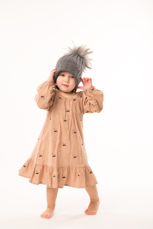 Portrait of happy little girl. Cute little girl in beige dress in a gray hat isolated on white background.の写真素材