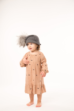 Portrait of happy little girl. Cute little girl in beige dress in a gray hat isolated on white background.の写真素材
