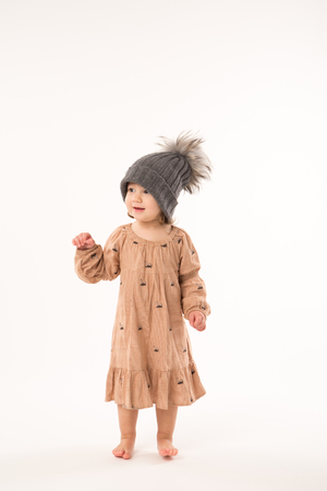 Portrait of happy little girl. Cute little girl in beige dress in a gray hat isolated on white background.の写真素材