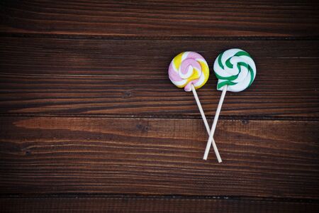 Round colored candies on a wooden background. The concept of childhood and food.の写真素材