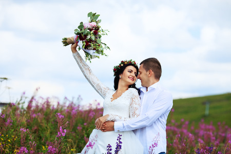 A young man holds the bride in the mountains. The concept of marriage and love.の写真素材