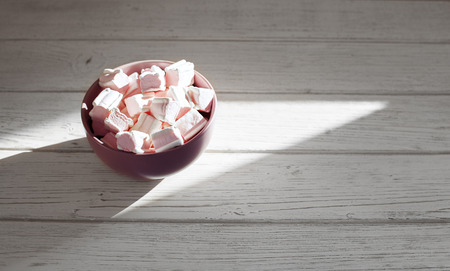 Marshmellow in a bowl on a wooden background. The concept of food.の写真素材