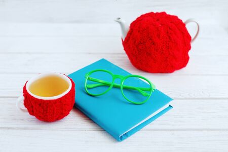 The book, glasses, a cup of tea and teapot on a wooden table. The concept of learning and work.の写真素材
