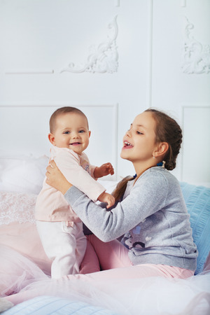 older sister plays with the baby in the room. The concept of childhood and educationの写真素材
