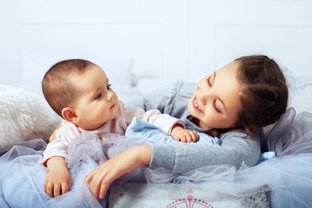 The big sister is in bed with the infant. The concept of family and lifestyle.の写真素材