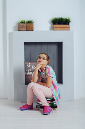 Clever girl schoolgirl sitting with books. The concept of childhood and education.の写真素材