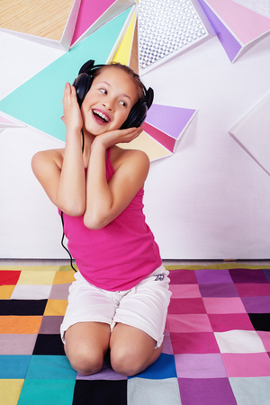 Beautiful happy child girl listening to music and singing. The concept of childhood and music.の写真素材