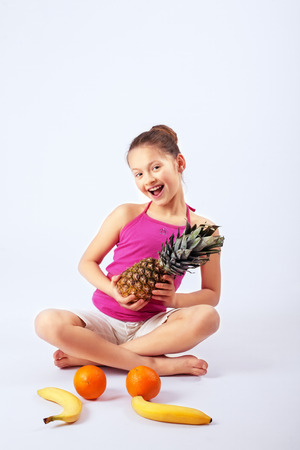 Happy child has oranges, pineapple and banana. The concept of healthy eating and vegetarianism.の写真素材