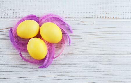 Yellow eggs with feathers on a white background. Top view. The concept of a happy Easter.の写真素材